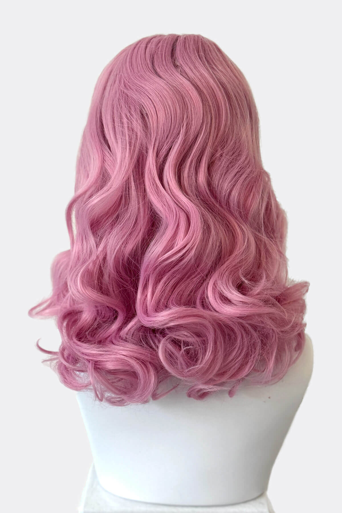 Pink wig on a white mannequin head against a white background. Pink pinup style wig, with finger waves and a short fringe, 1950s style: Stevie light pink 2614
