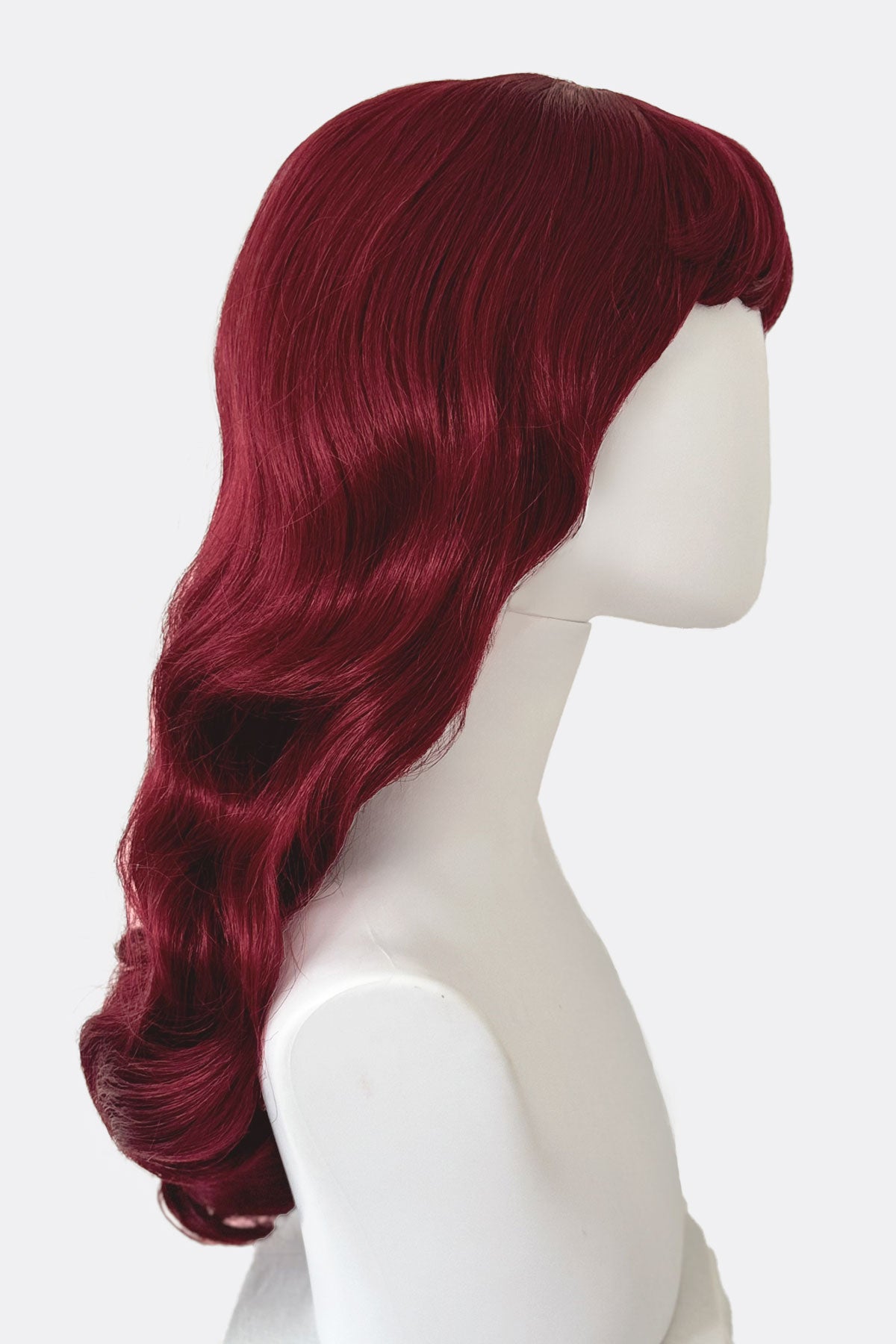 Red wig on a mannequin head against a white background. Long cherry red pin-up wig, gently wavy with short fringe: Maeve