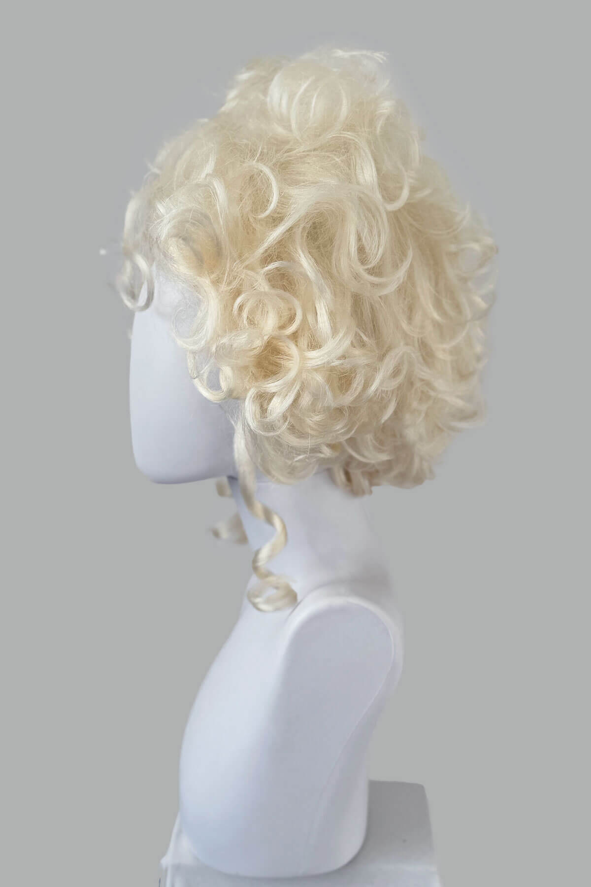 Blonde wig on a mannequin head against a gray background. Platinum blonde Marie Antoinette style wig: Marie platinum blonde 1001