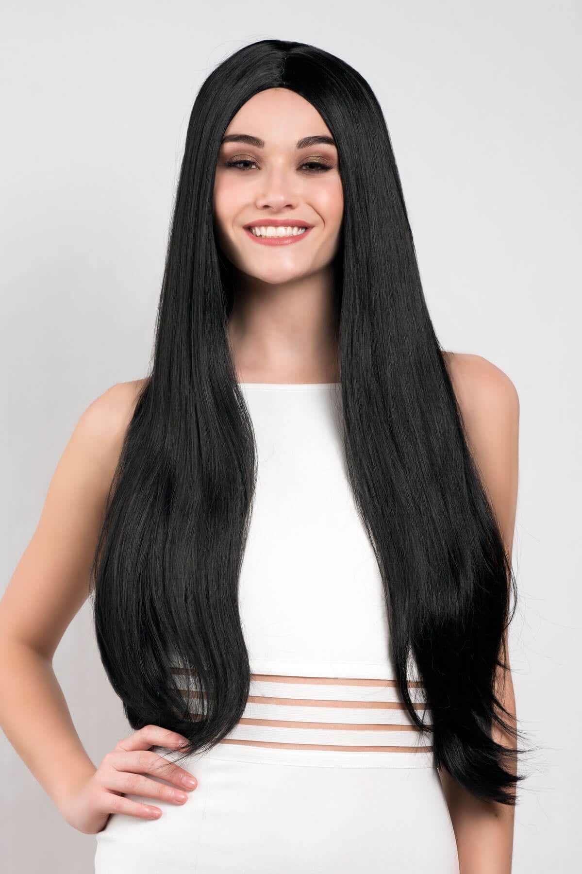 Woman wearing a black wig on a plain background. Long straight black wig with no fringe: Madeline