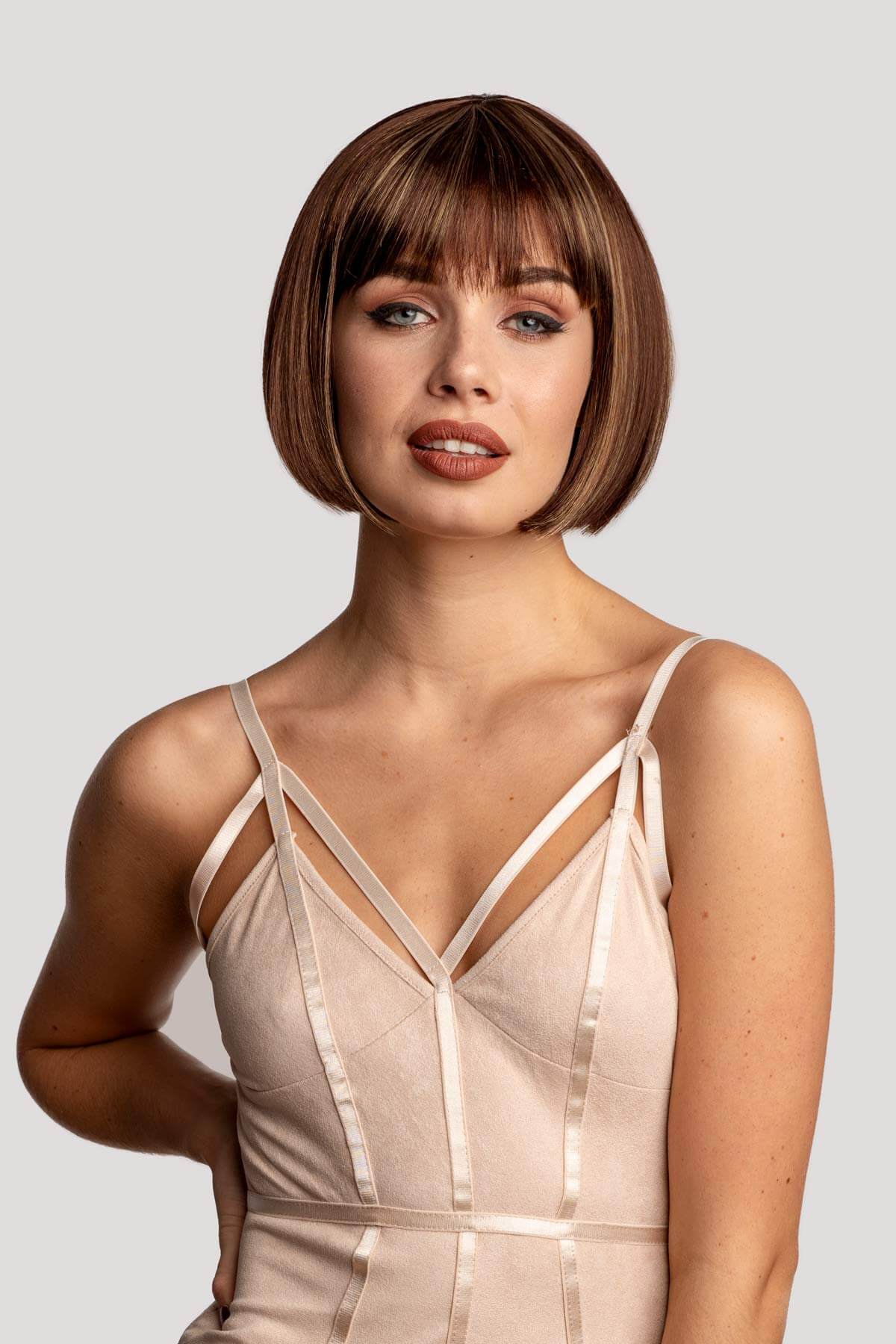 Woman wearing a beige slip dress against a plain background. Brown bob wig with blonde highlights: Bethany
