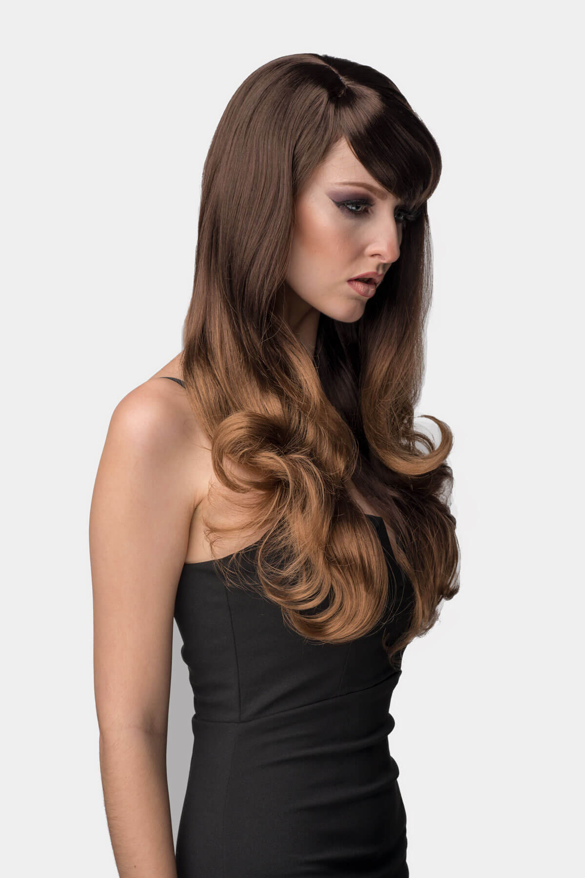 Woman with long, wavy brown hair styled in a side part against a white background. Long ombre wig - dark brown blending to blonde: Rey