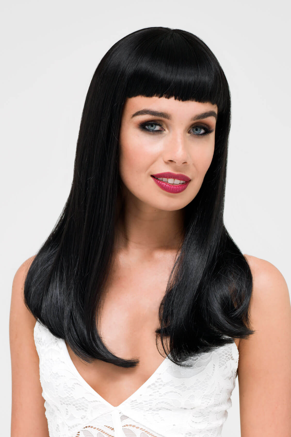 Woman with long black hair and a white top on a light gray background. Long black wig with straight hair and a short, straight fringe: Maxine