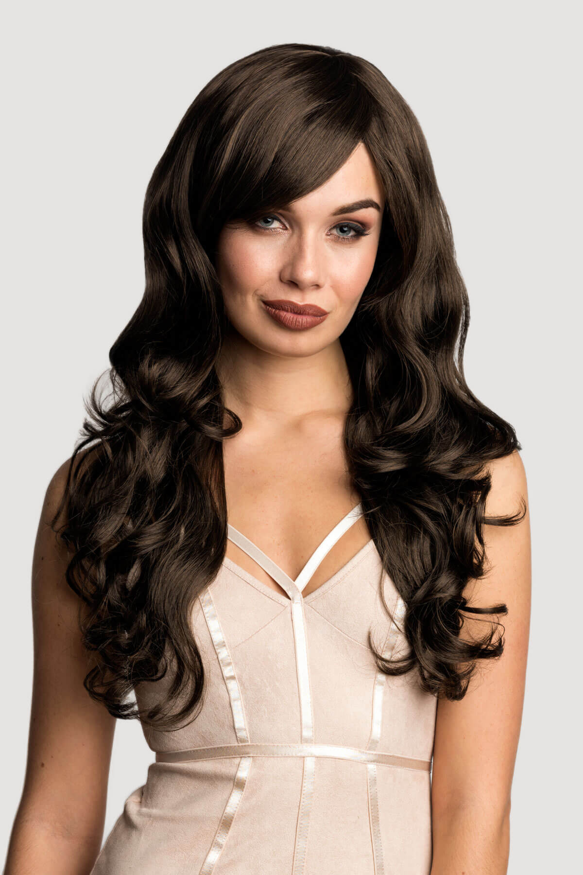 Woman with long, wavy brown hair wearing a beige dress on a light grey background. Long brown wig with gentle waves: Bella chestnut brown 8