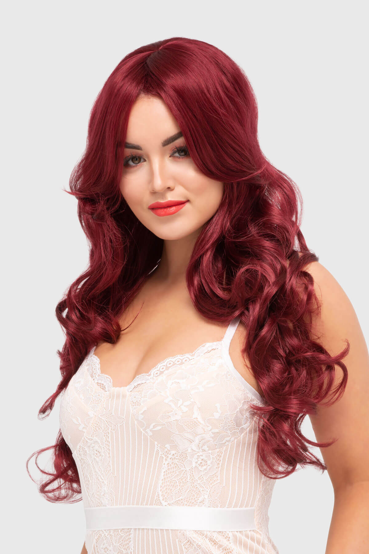 Woman with long, wavy red hair wearing a white lace top on a light gray background. Long red wig with loose curls: Peggy Soo