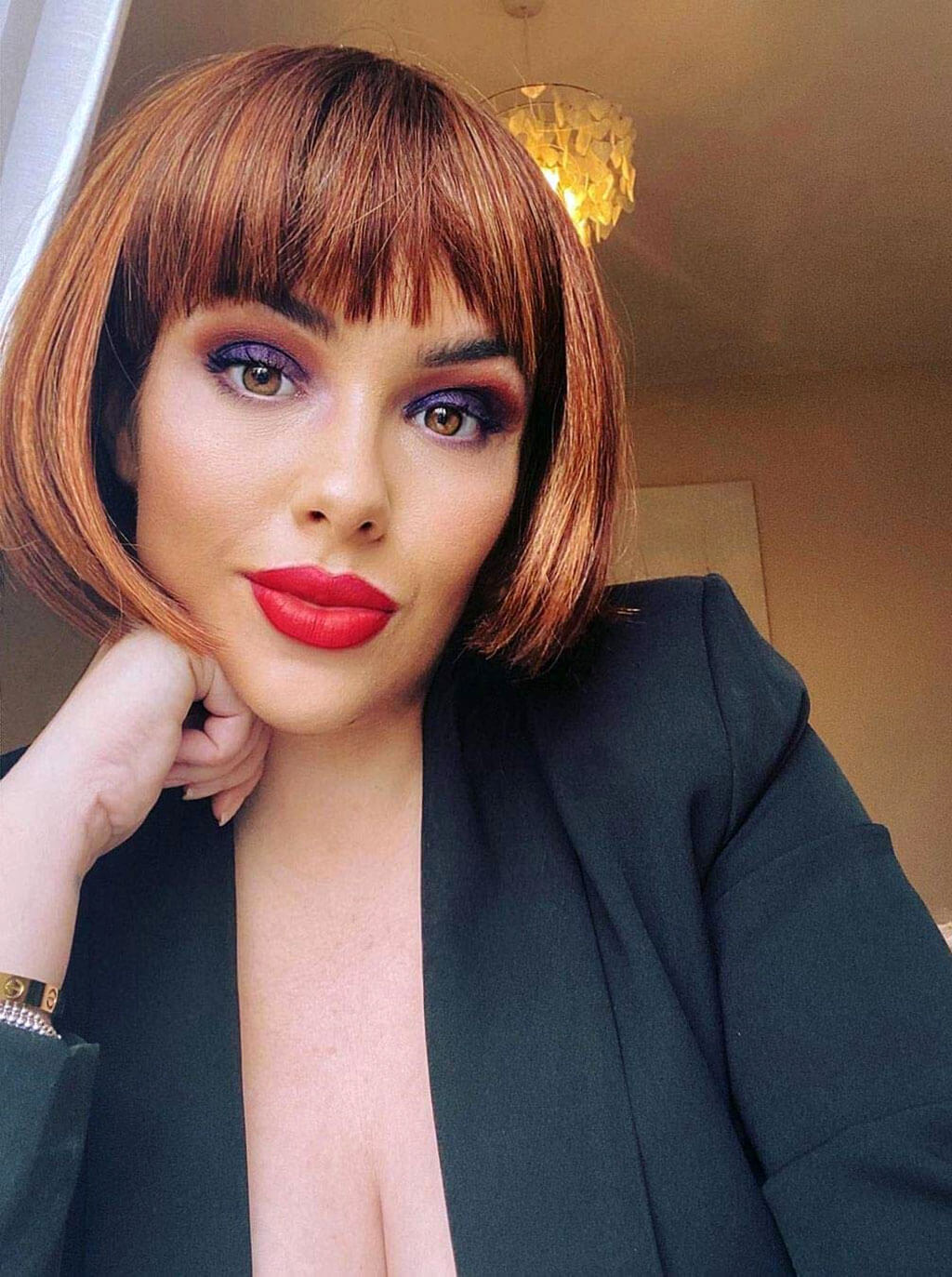 Woman with a stylish haircut and makeup indoors. Copper red wig, bob style: Siren