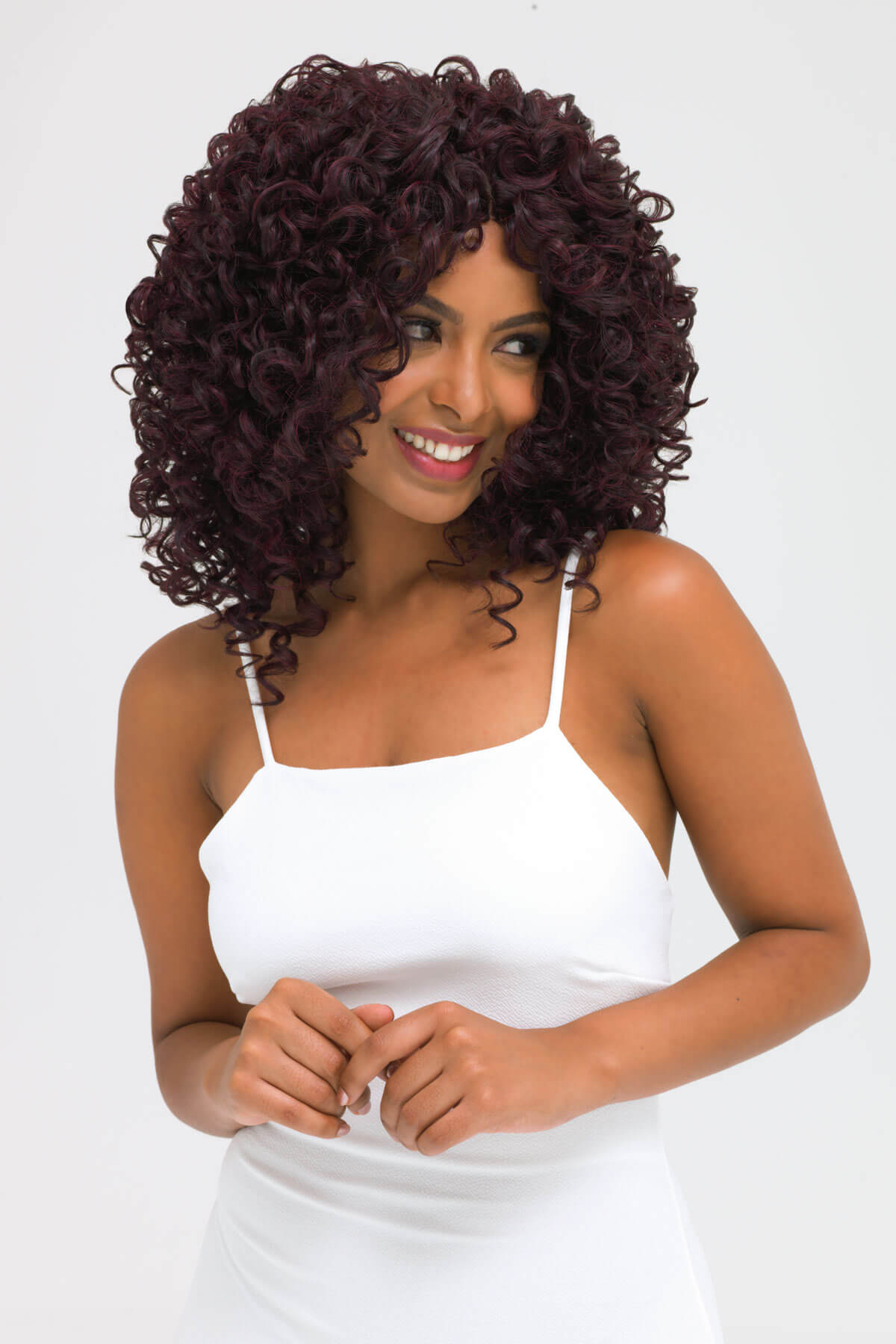 Woman with curly brown hair wearing a white dress on a white background. Afro, corkscrew curly lace front wig, black and purple: Anna