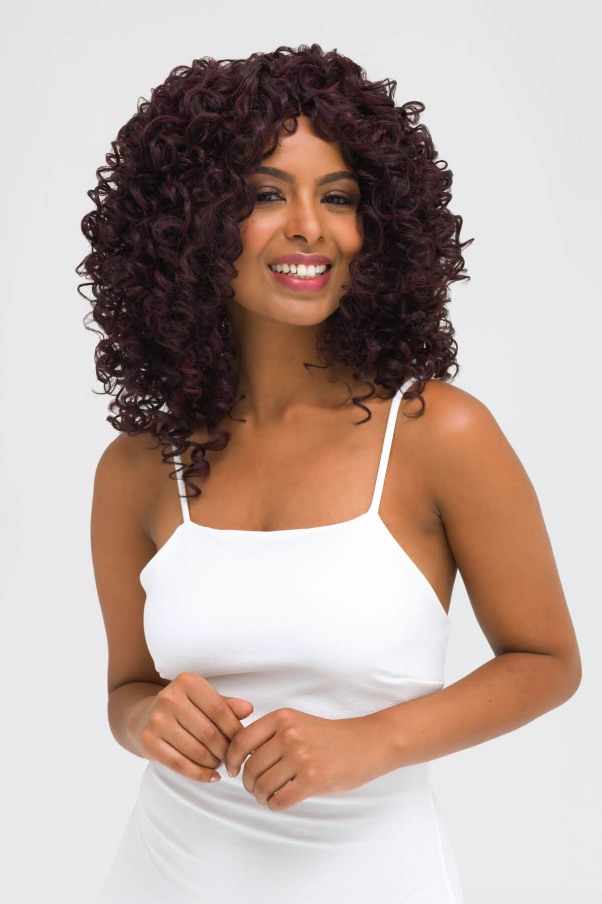 Woman with curly hair wearing a white dress on a white background. Afro, corkscrew curly lace front wig, black and purple: Anna