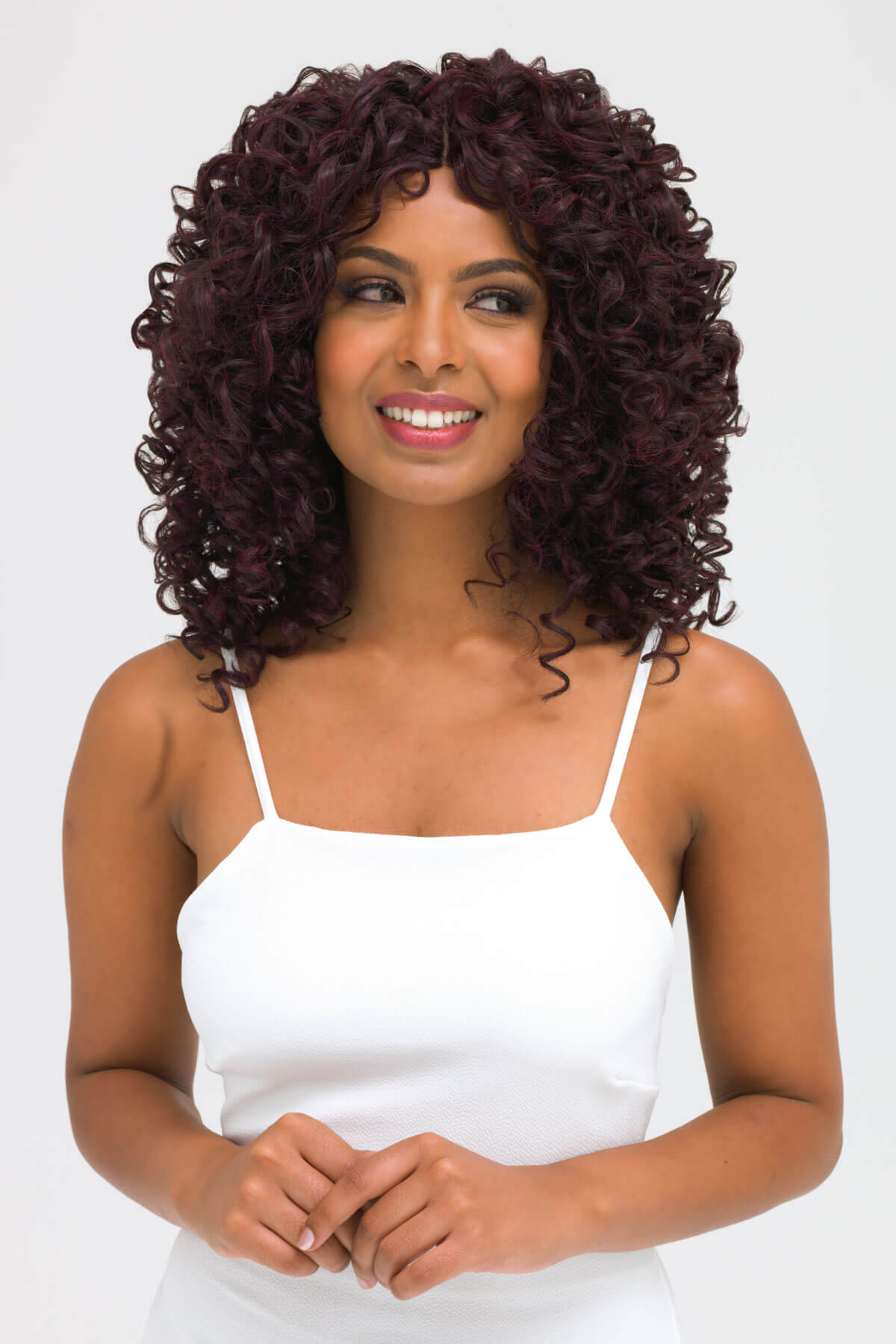 Woman with curly hair wearing a white tank top on a white background. Afro, corkscrew curly lace front wig, black and purple: Anna