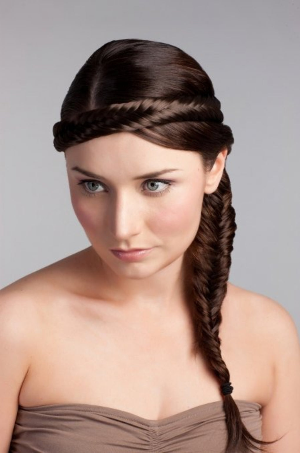 A woman wearing a fishtail plait hairband with a side braid, in a brown dress, with a neutral background. Fishtail plait hairband (braid)