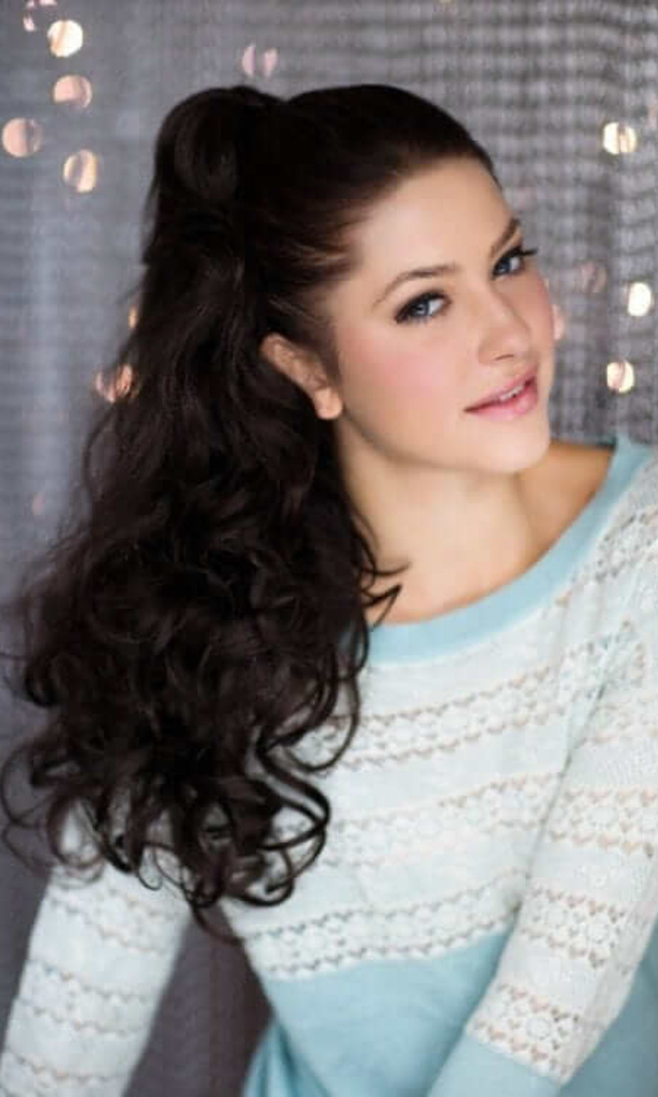 A woman wearing a long wavy ponytail hairpiece extension with loose and layered curls. Long wavy ponytail hairpiece extension: Tiffany