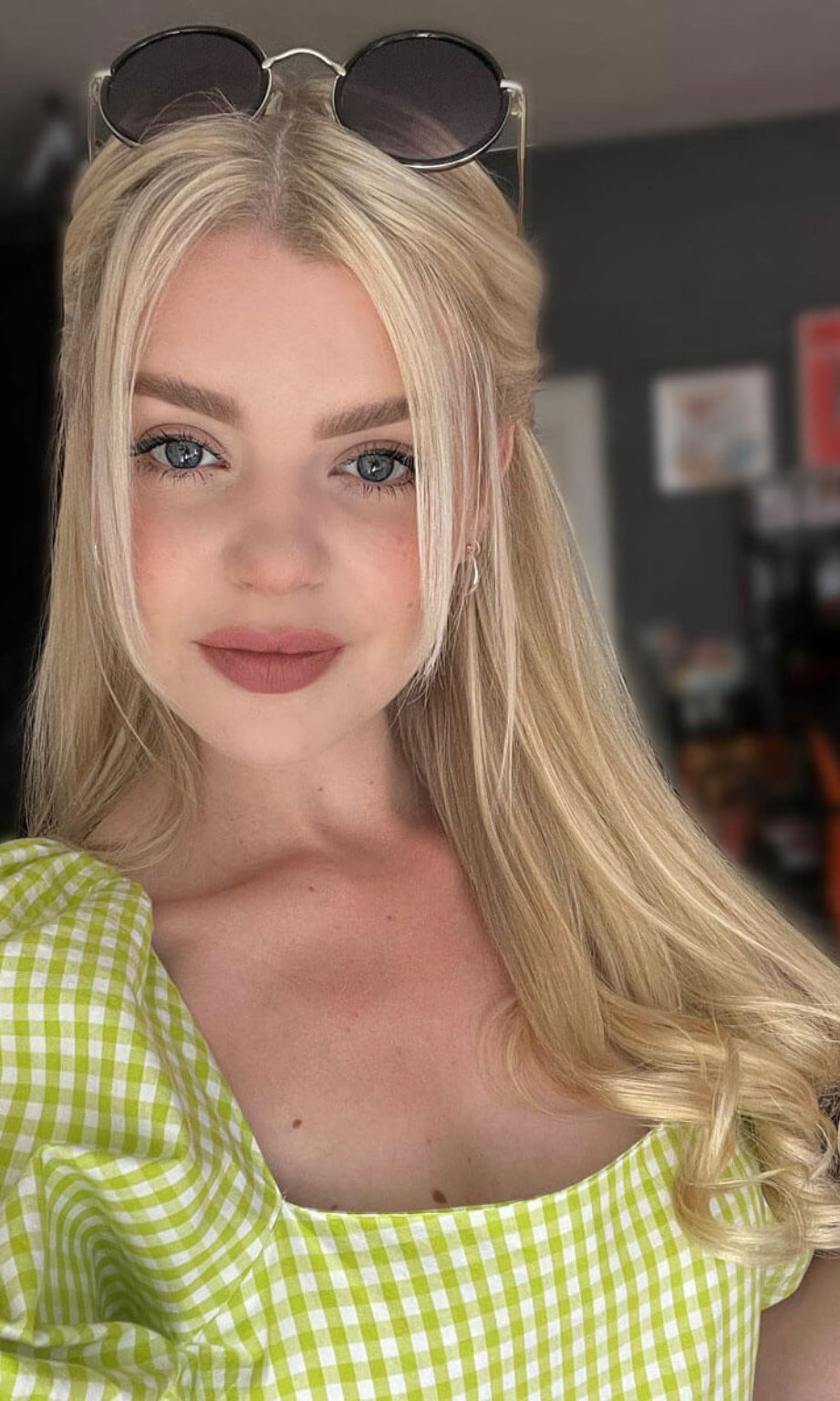 A woman with long blonde hair wearing a green checkered top and sunglasses on her head. Human Hair Extensions, remy hair 613T24