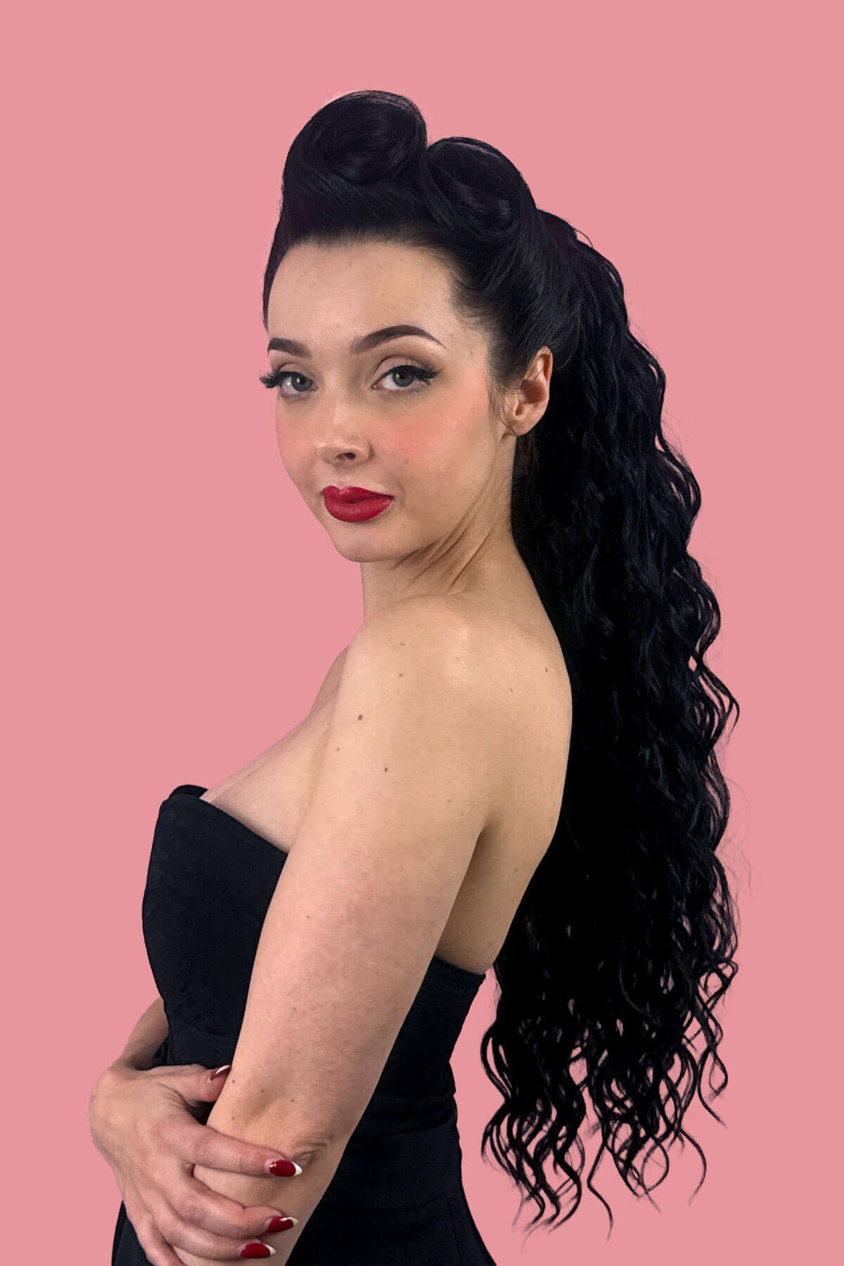 A woman in profile wearing a black strapless dress, showcasing a long, dark, curly wavy hair extension against a solid pink background. Long Curly Ponytail Hair Piece Extension, Black