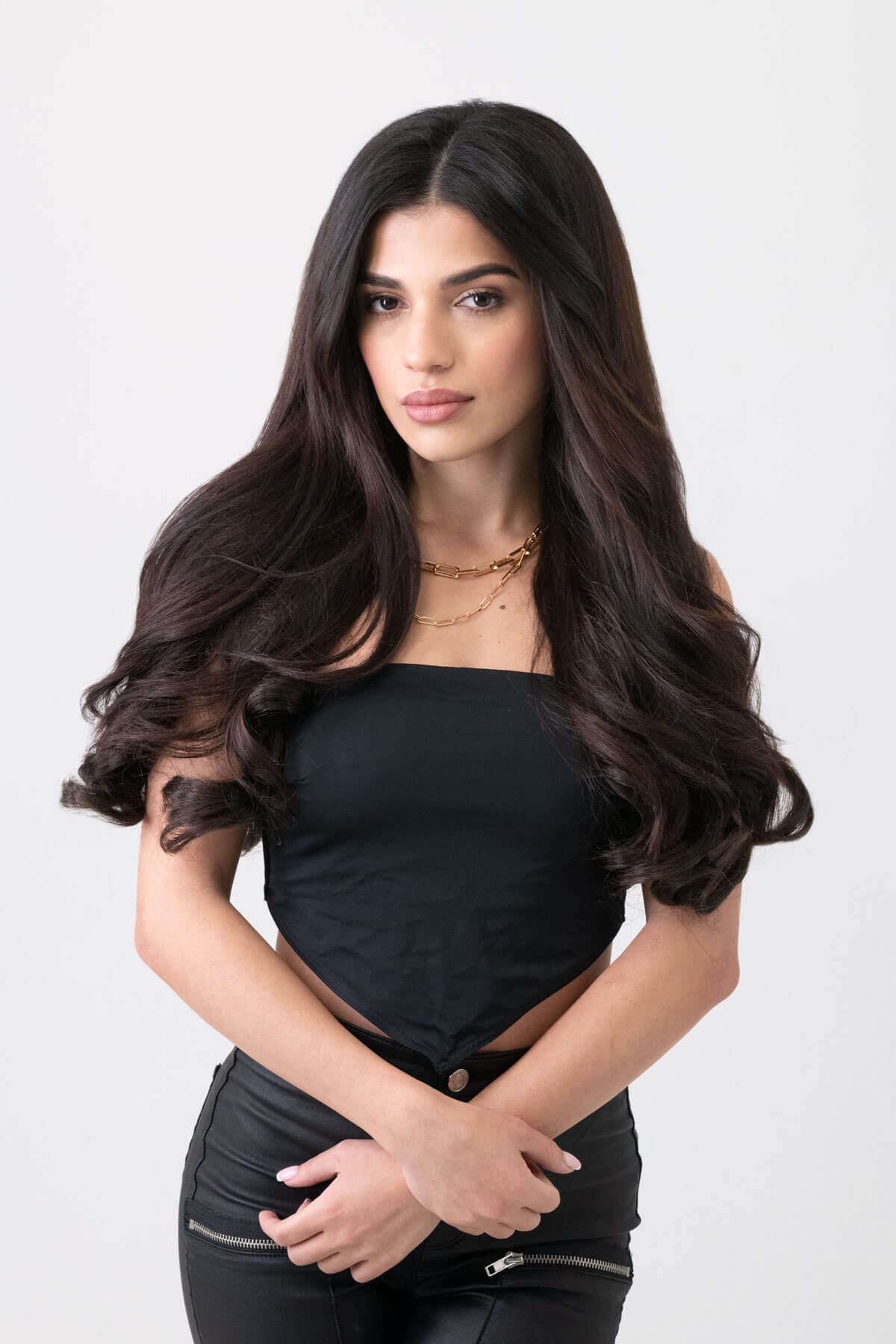 Woman with long, wavy hair wearing a black outfit on a white background