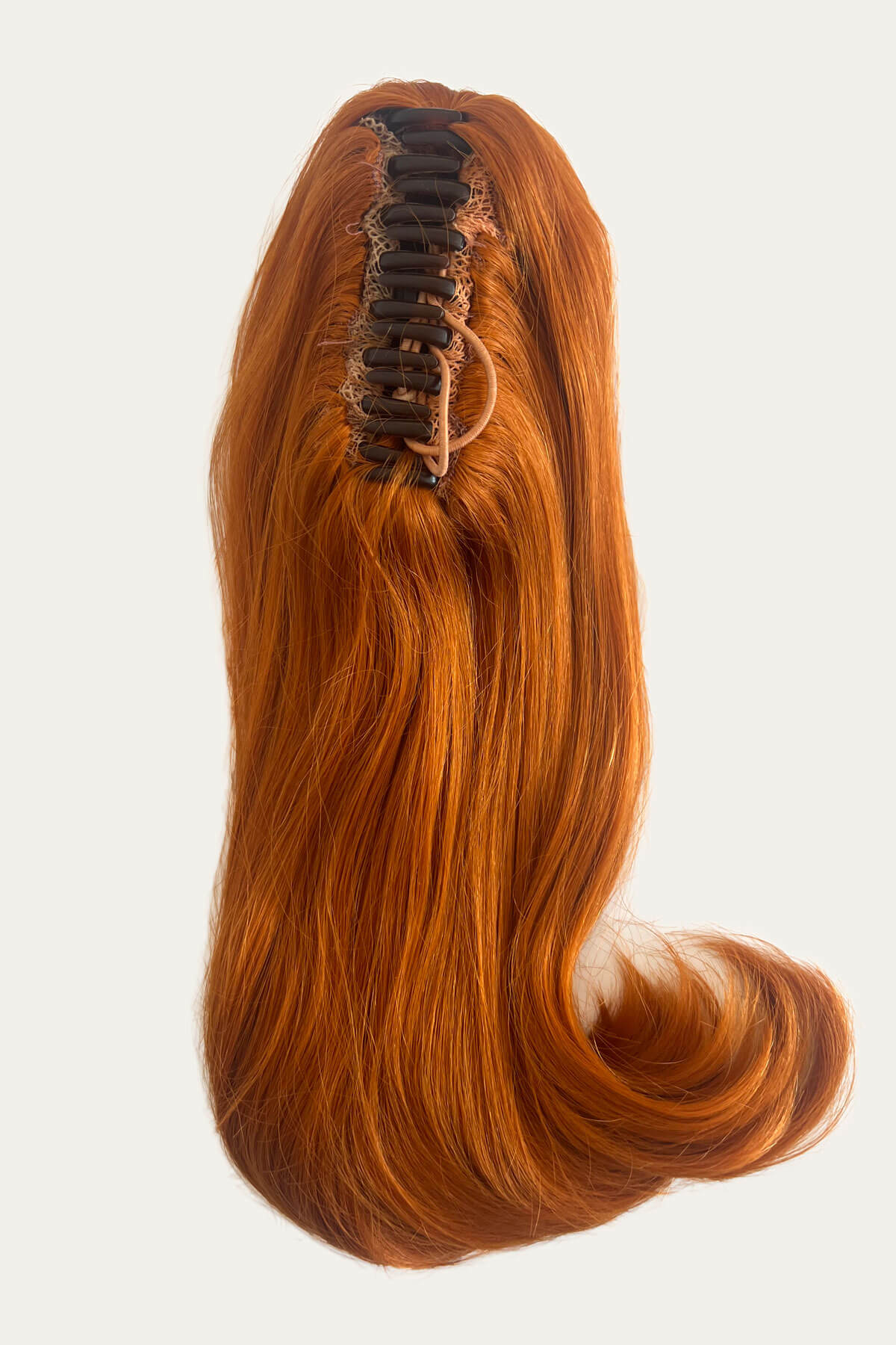Reddish-brown hair extension with a clip on a white background. Ponytail hairpiece, shoulder length with flick/flip, retro 1960s style: Ariana Ginger