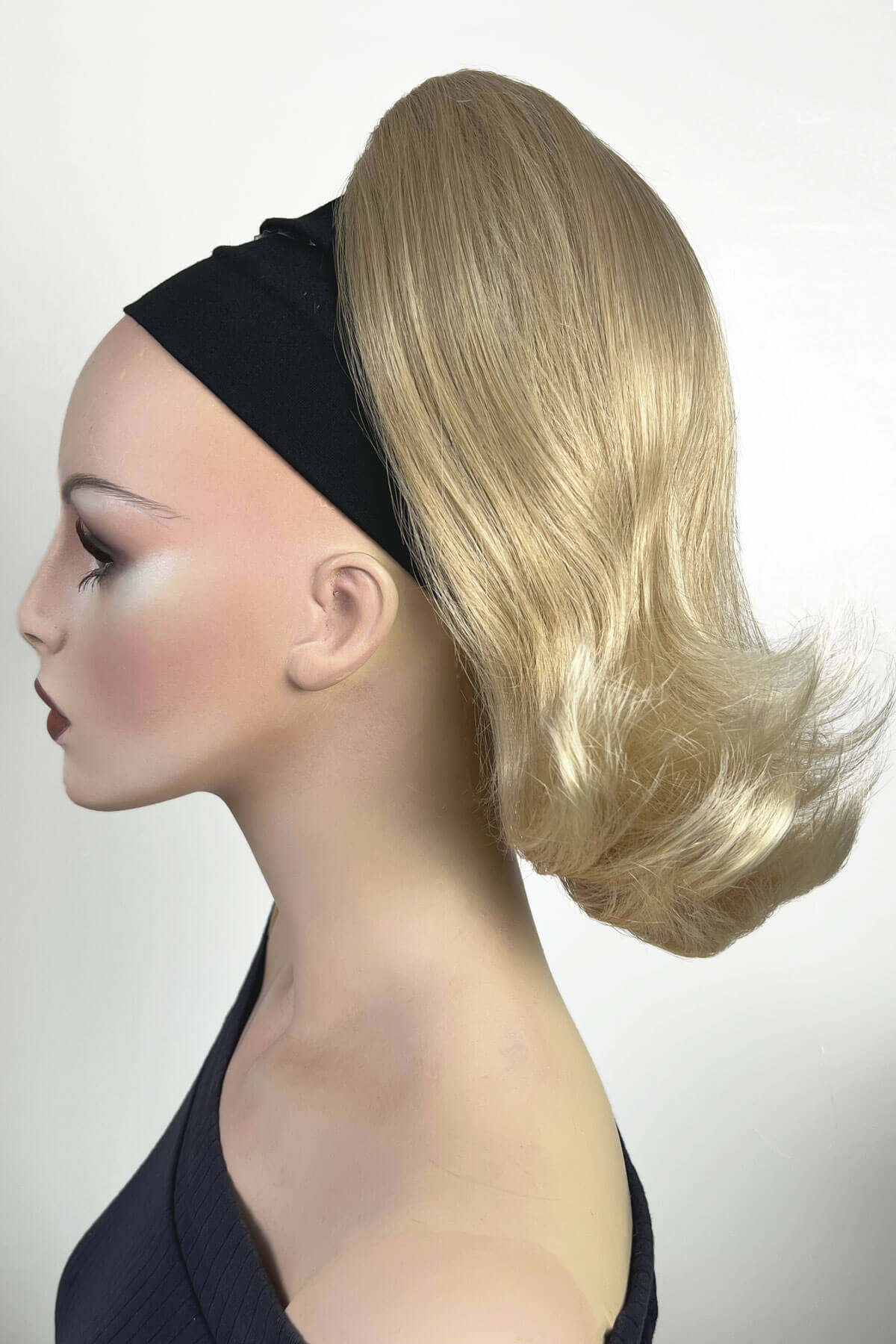 Mannequin head with blonde wig and black headband on a white background. Ponytail hairpiece, shoulder length with flick/flip, retro 1960s style: Ariana blonde 613T24