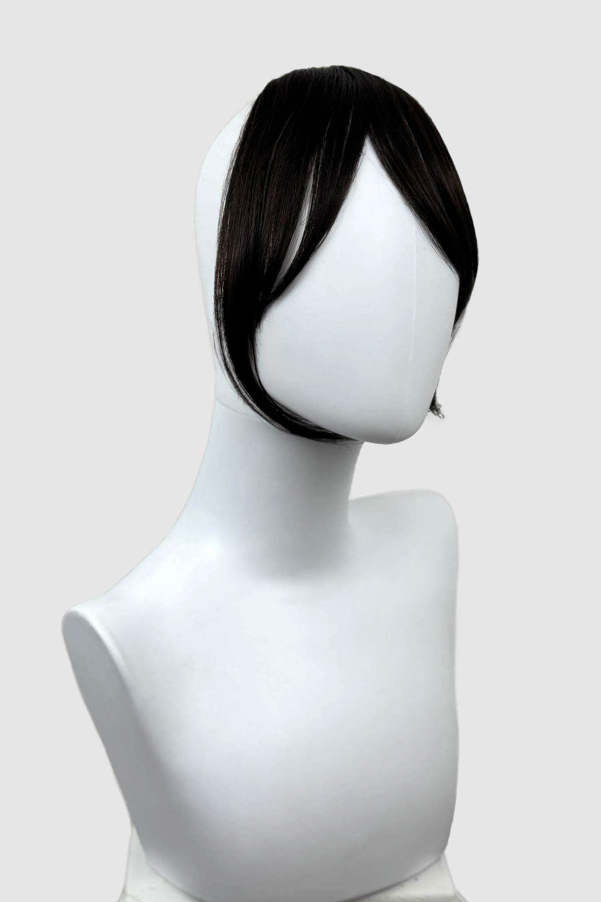 Black wig on a mannequin head against a white background. Clip in fringe hairpiece/clip-in curtain bangs, with long, face framing wisps: Sabrina dark brown 4