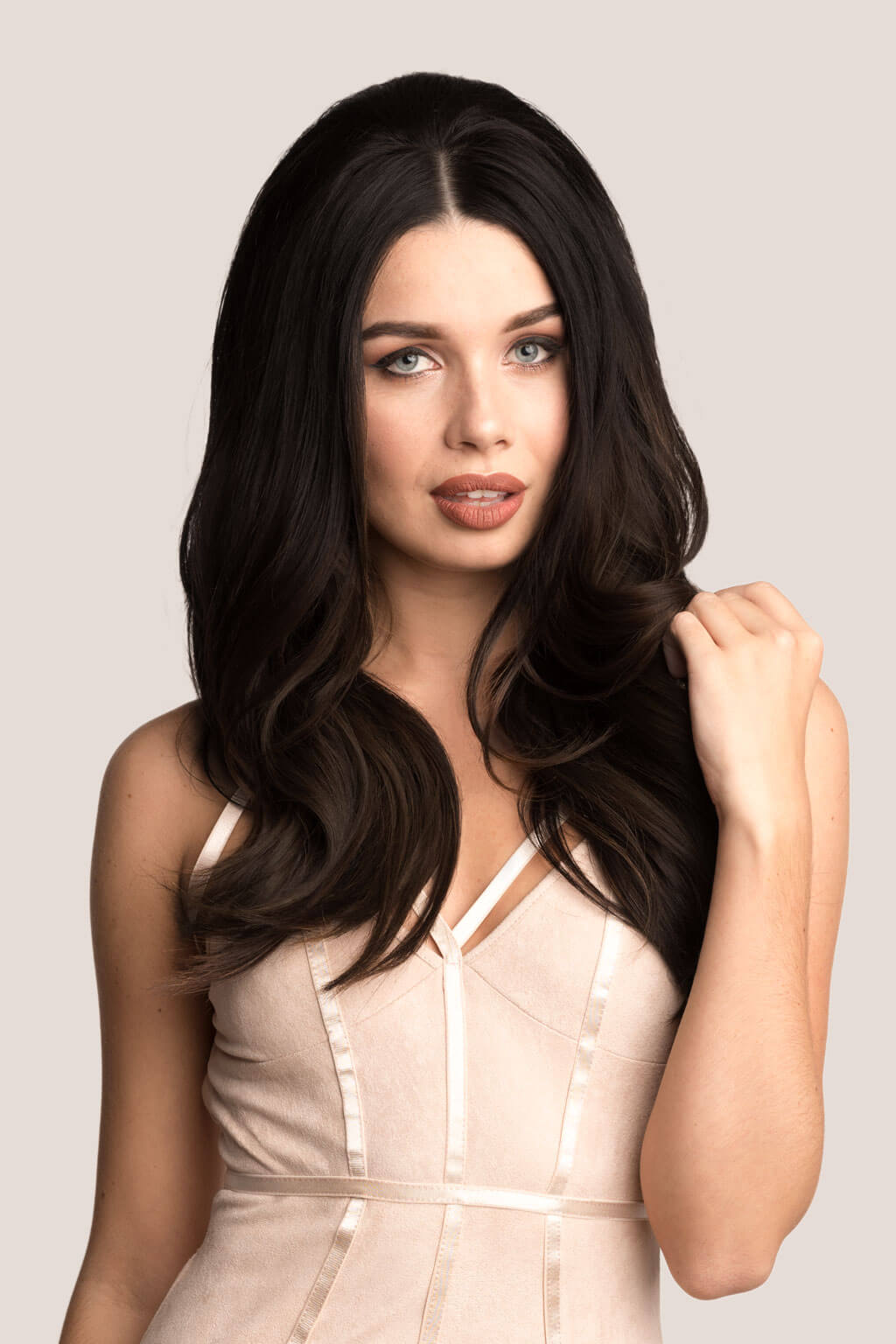 Woman with long, dark hair wearing a beige dress against a light background
