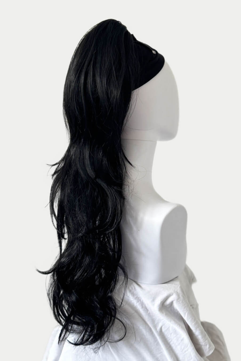 Black hair wrap on a mannequin head against a white background. Clip-in ponytail hairpiece extension: Olivia black 1B