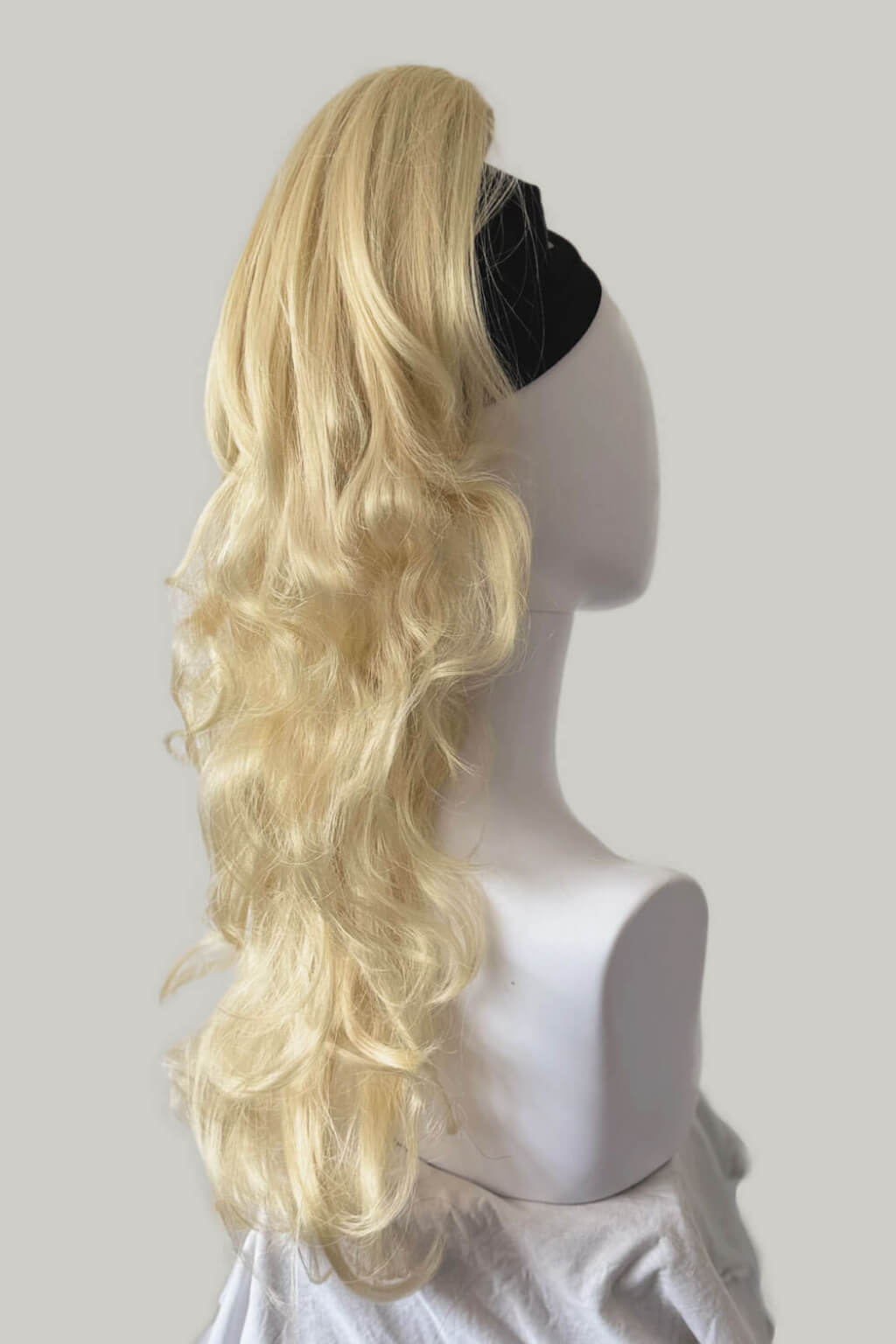 Blonde wig on a mannequin head against a plain background. Clip-in ponytail hairpiece extension: Olivia creamy blonde 613