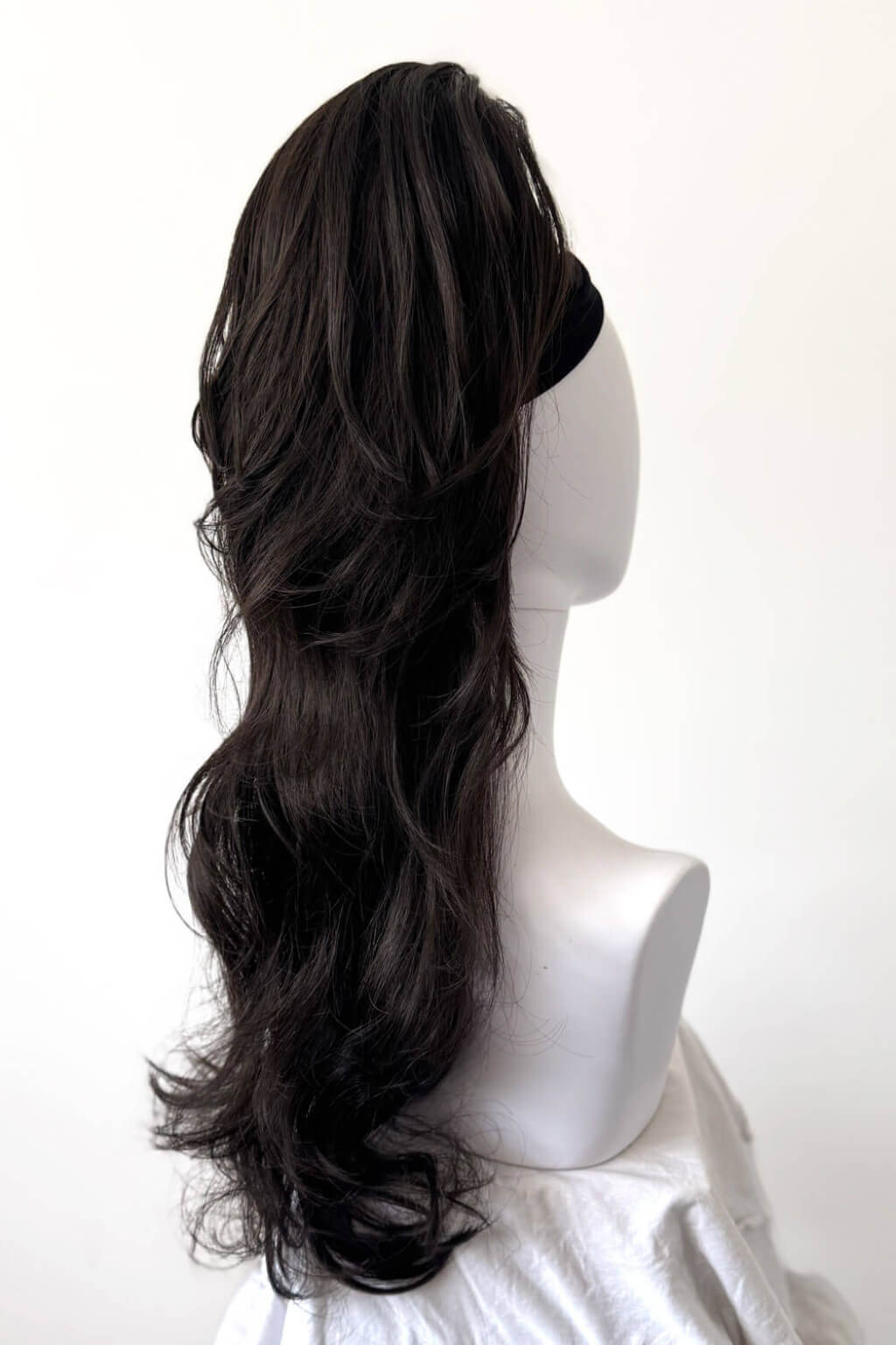 Dark brown hair extension on a mannequin head against a white background. Clip-in ponytail hairpiece extension: Olivia dark brown 4