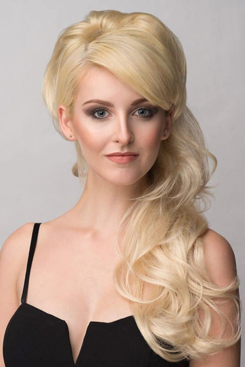 Woman with styled blonde hair against a plain background. Double volume hairpiece extension with gentle waves: Naomi blonde 613T24