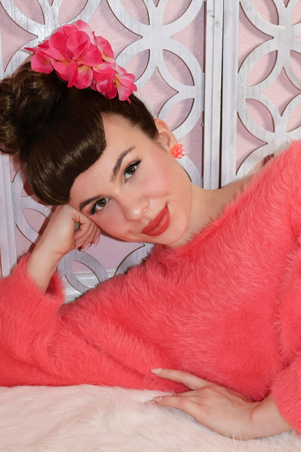 Woman in a pink robe with a decorative headpiece against a white lattice background. Victory roll fringe/bangs, 1950s vintage style: Rosa