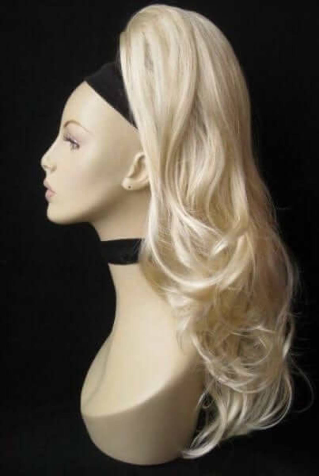 Blonde wig on a mannequin head against a black background. Wavy, long ponytail hairpiece extension: Casey champagne blonde 613
