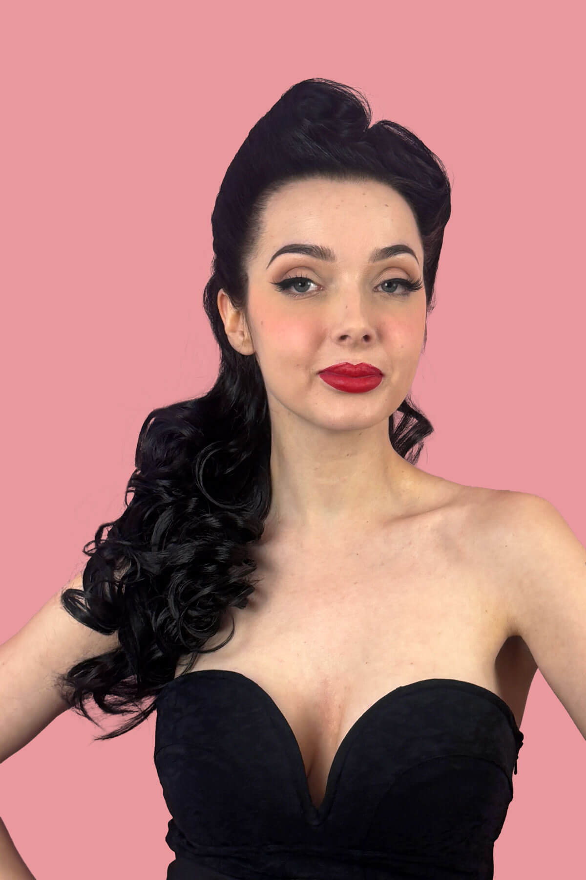 Woman in a black dress with red lipstick against a pink background. Long wavy ponytail hairpiece extension: Tiffany black 1B