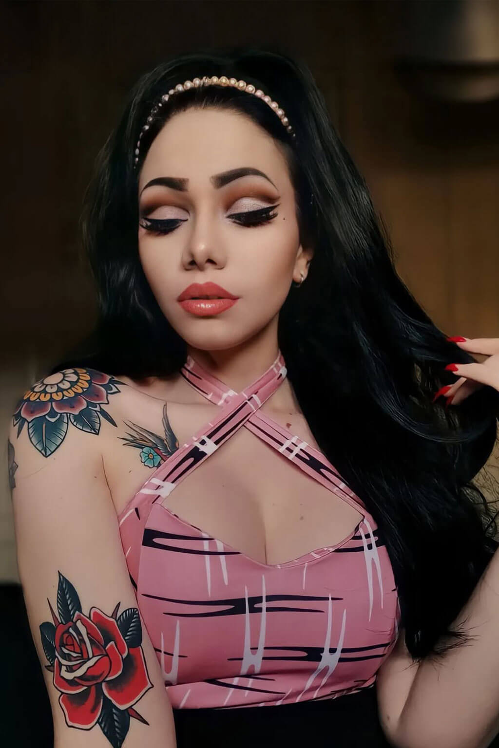 Woman with tattoos and a pink top posing indoors. High crown long, wavy half wig and volume ring: Bardot jet black 1