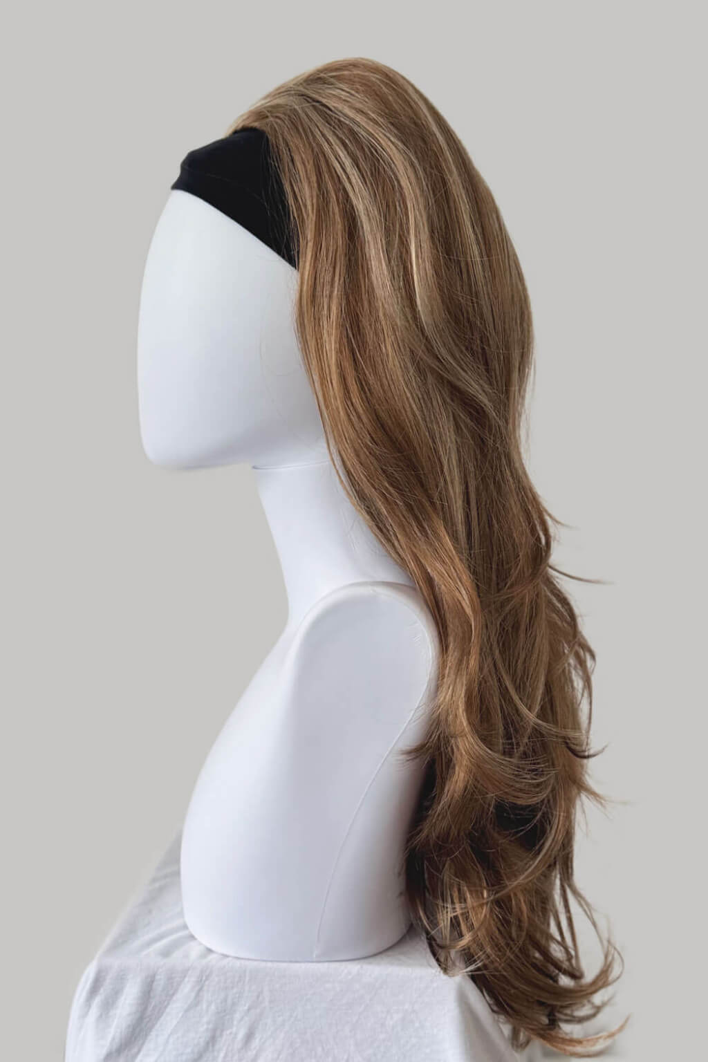 Mannequin head with long brown wig on a plain background. High crown long, wavy half wig and volume ring: Bardot brown blonde mix 27H613