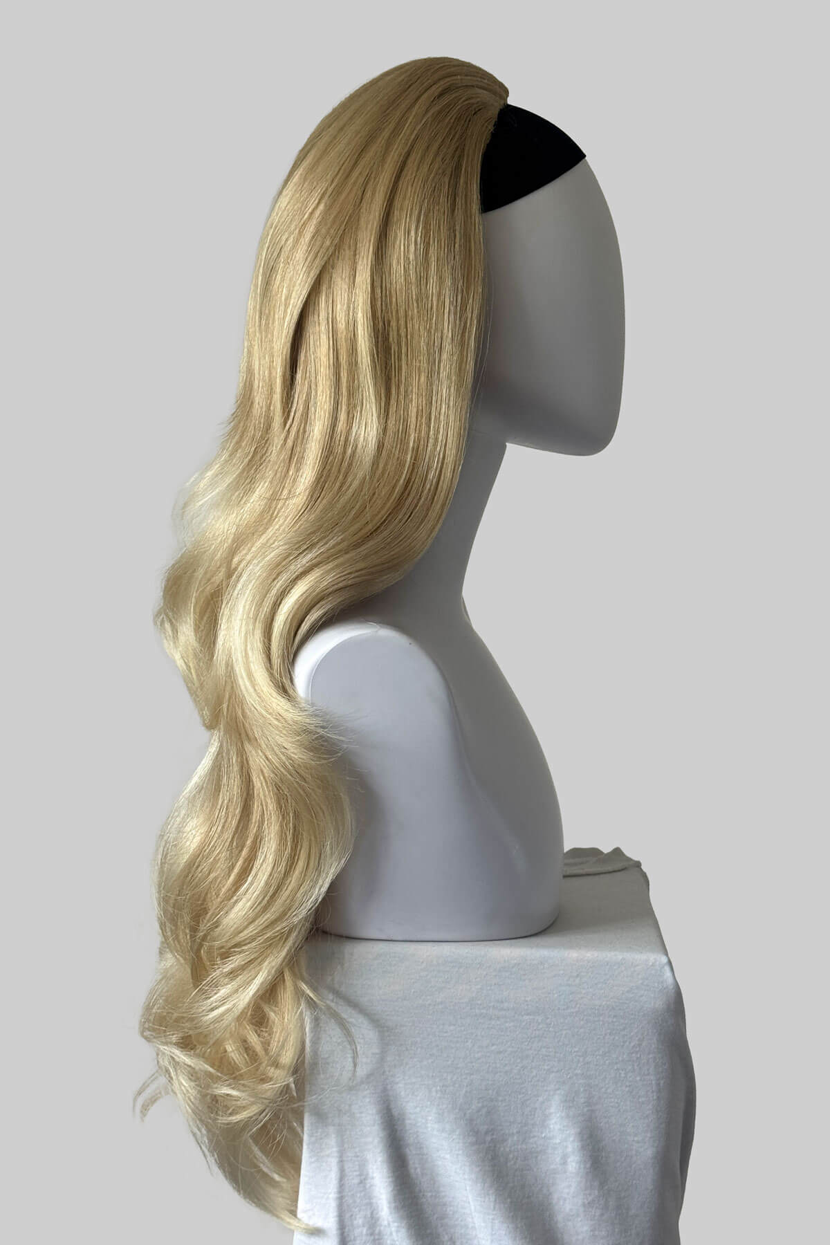A long blonde half wig with soft waves and a black top band, displayed on a white mannequin head against a light grey background. Corrine - Bouncy Blowout style with Volume Booster Half Wig blonde 613T24