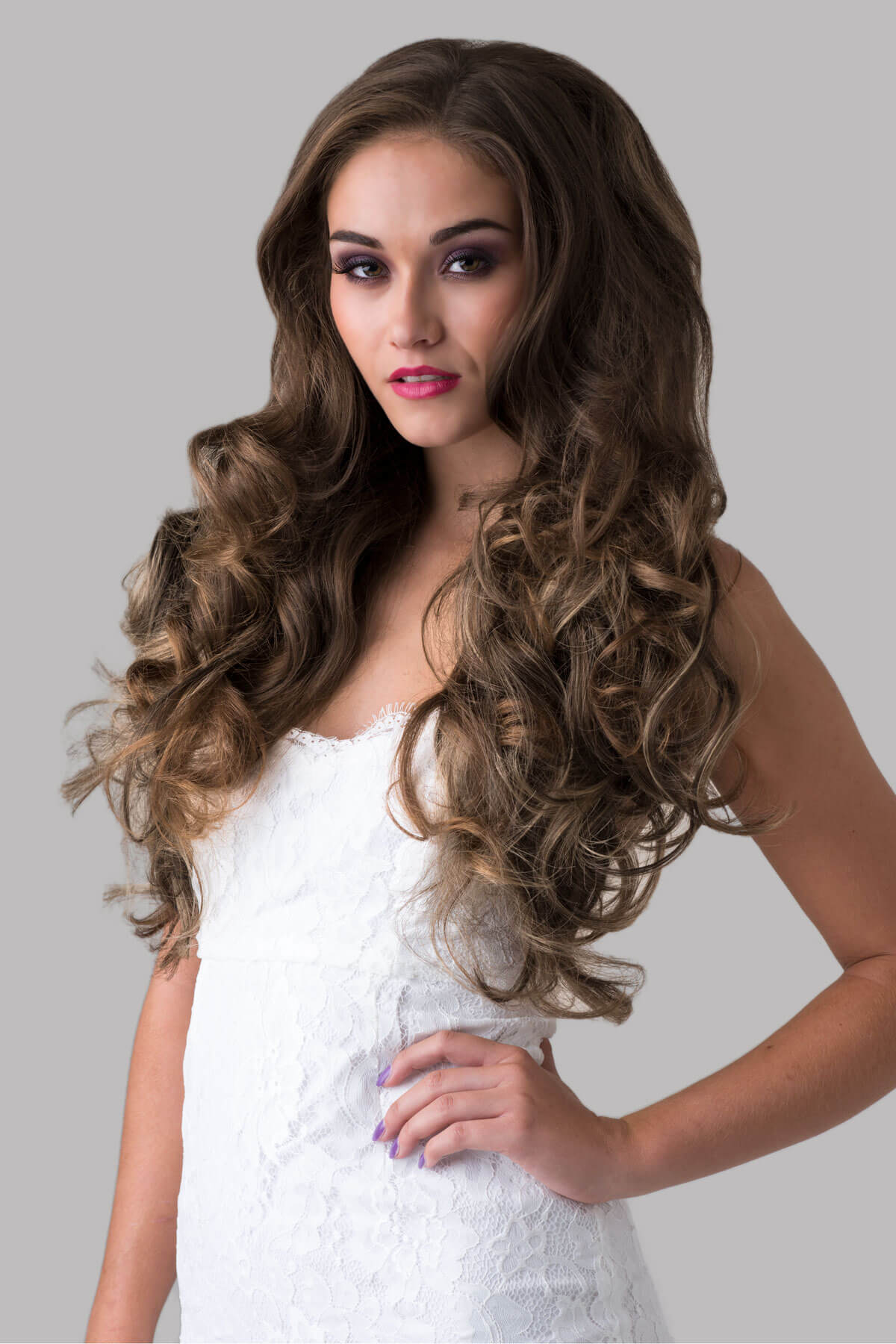 Woman with long, wavy hair styled in a half-up, half-down look against a plain background. Brown half wig with blonde highlights with big loose curls: Nickie