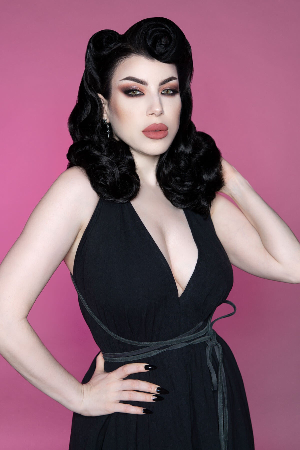 Woman in a black dress with a deep neckline against a pink background. 1950s style shoulder length half wig hairpiece with beautiful vintage waves: Onyx ginger