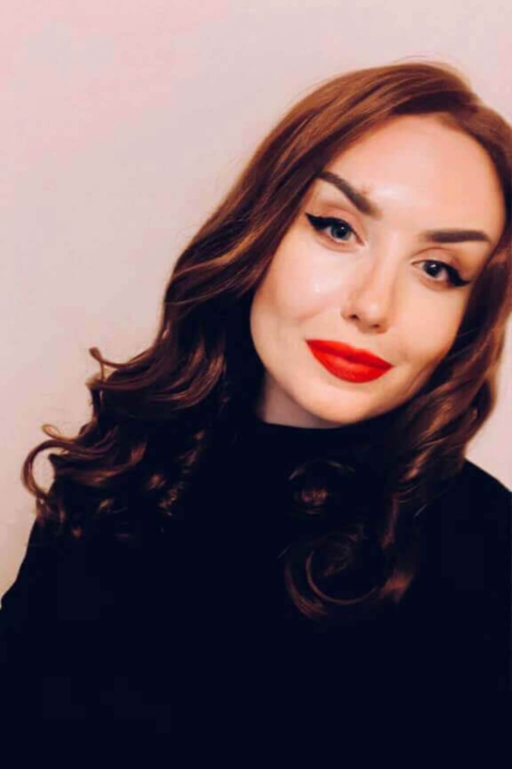 Woman with red lipstick and wavy hair against a plain background. Brown pinup wig, lace front with finger waves: Nikita colour chestnut brown 8