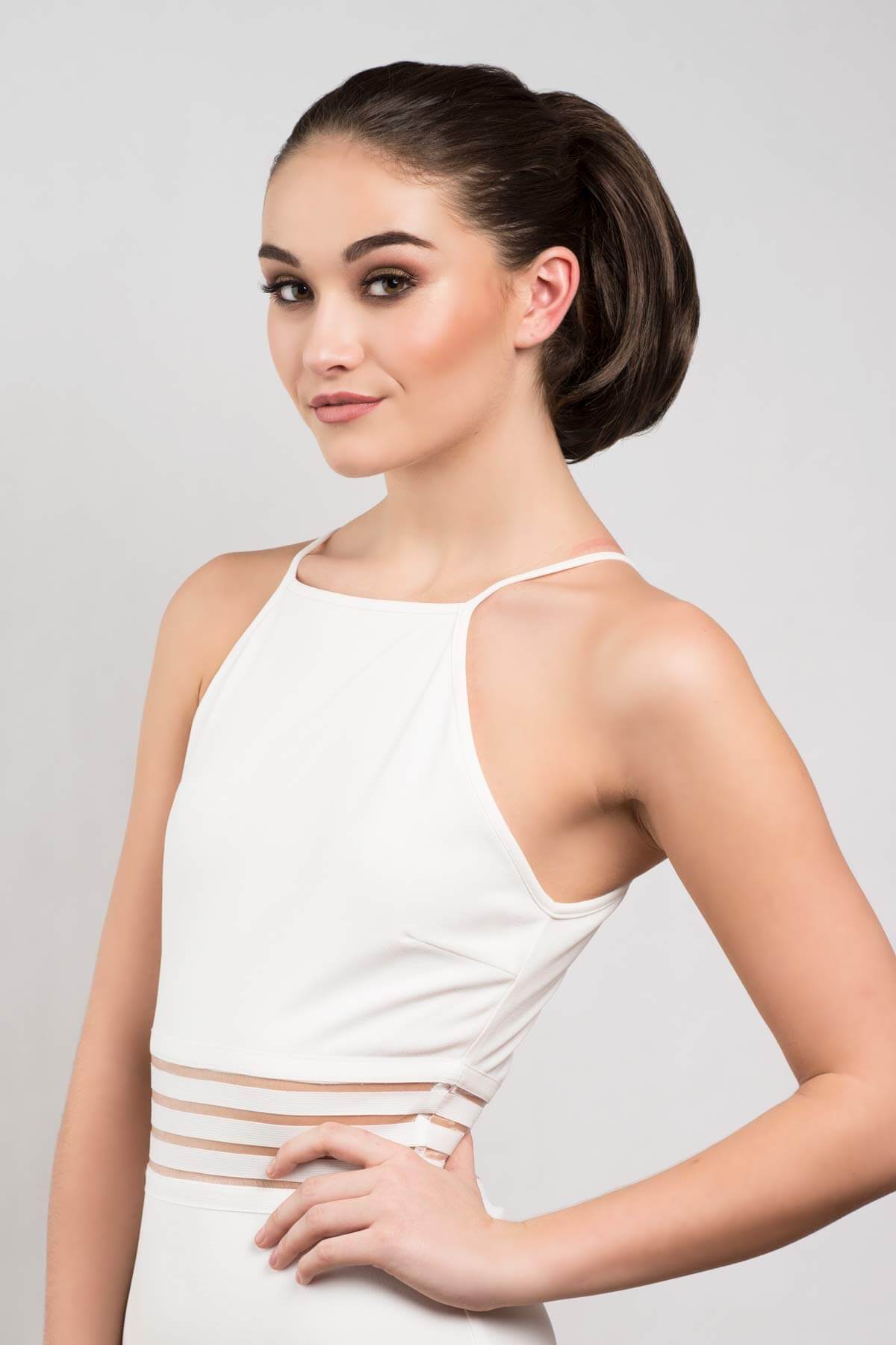 Woman wearing a white sleeveless dress with thin straps against a light gray background. Short ponytail extension hairpiece, straight, full & bouncy: Tanaya chestnut brown 8