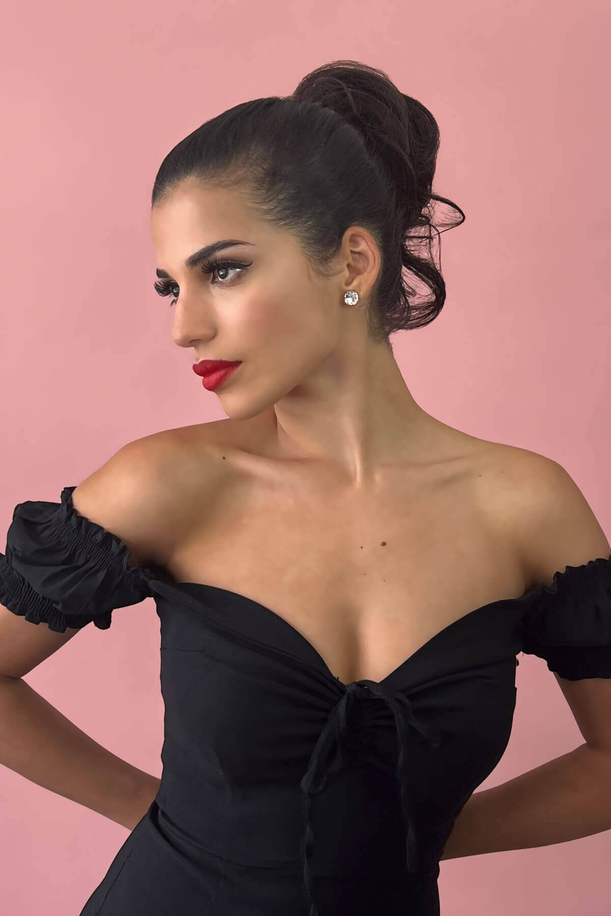 Woman in a black off-shoulder dress with red lipstick against a pink background. Short ponytail extension hairpiece, short with whisps: Leah ginger