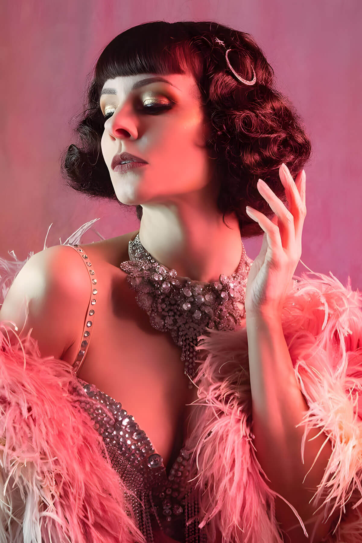Woman in a glamorous outfit with a feather boa against a pink background.  A short brown vintage style wig with waves: Rita chestnut brown 8