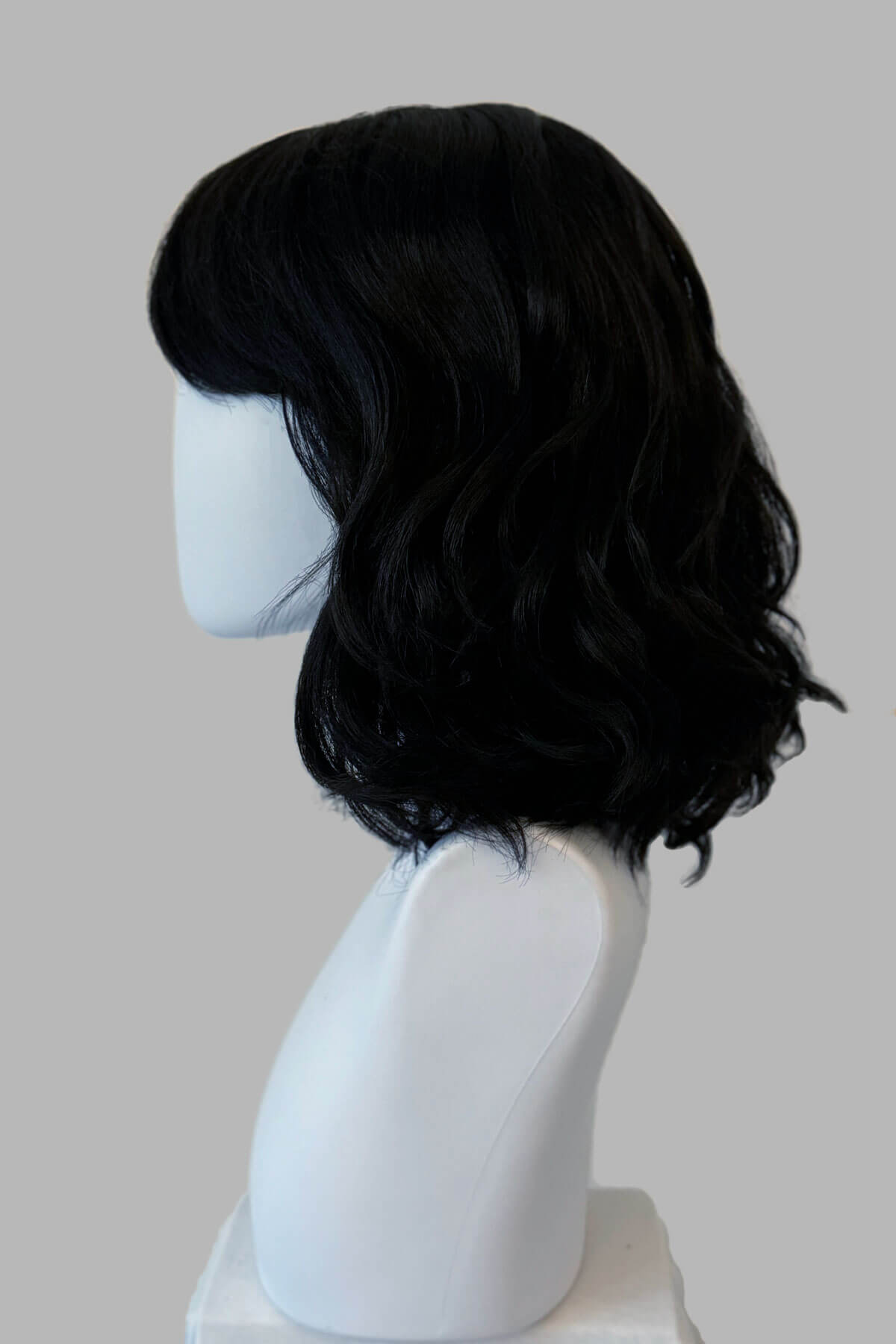 Black wig on a white mannequin head against a gray background. Black long wavy bob (lob) wig with swept fringe: Eleena