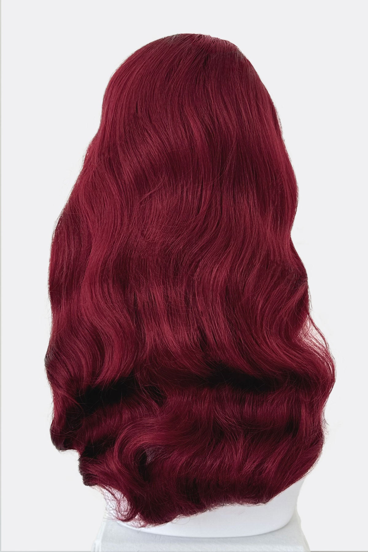 Red wig on a mannequin head, from behind, against a white background.  Long cherry red pin-up wig, gently wavy with short fringe: Maeve