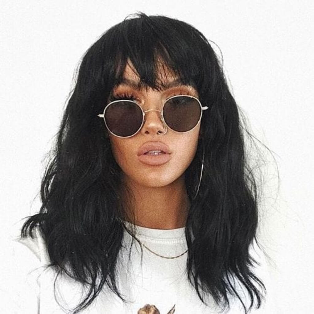 Person with long black hair and sunglasses on a white background. Black long wavy bob wig (lob): Sigrid