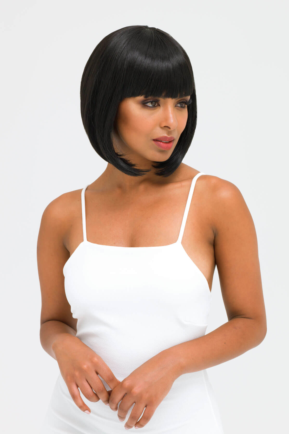Woman wearing a white dress with a plain background. Black inverted bob wig: Chloe