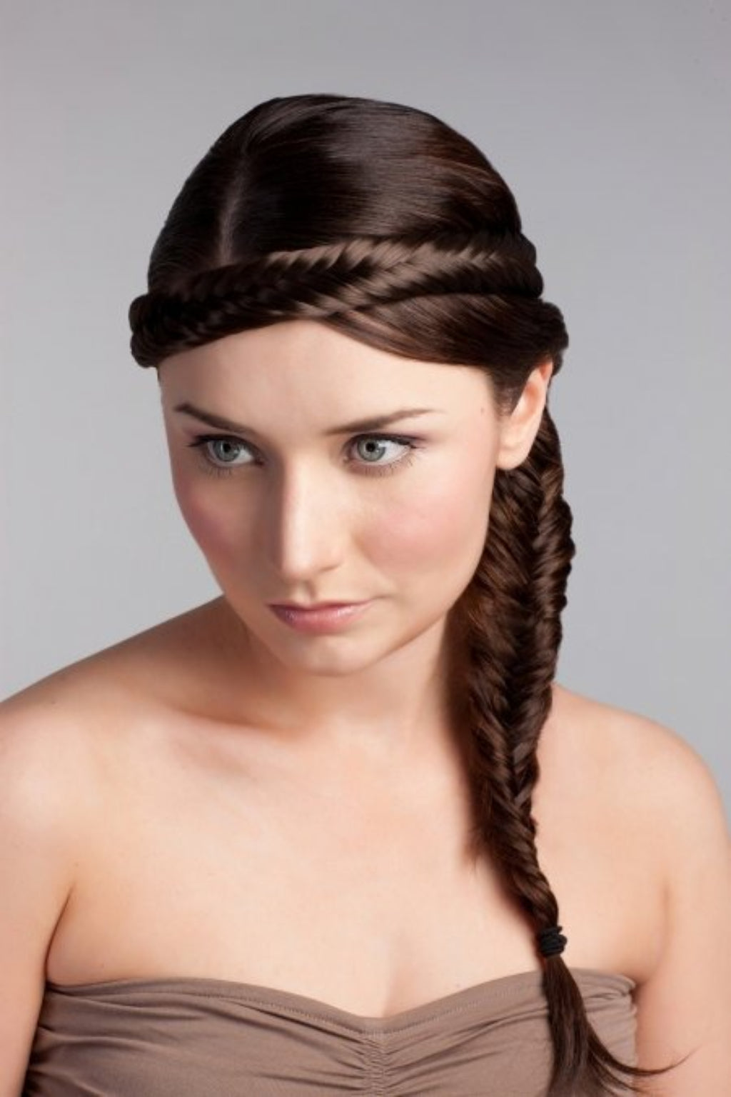 A woman wearing a fishtail plait hairband with a side braid, in a brown dress, with a neutral background. Fishtail plait hairband (braid)