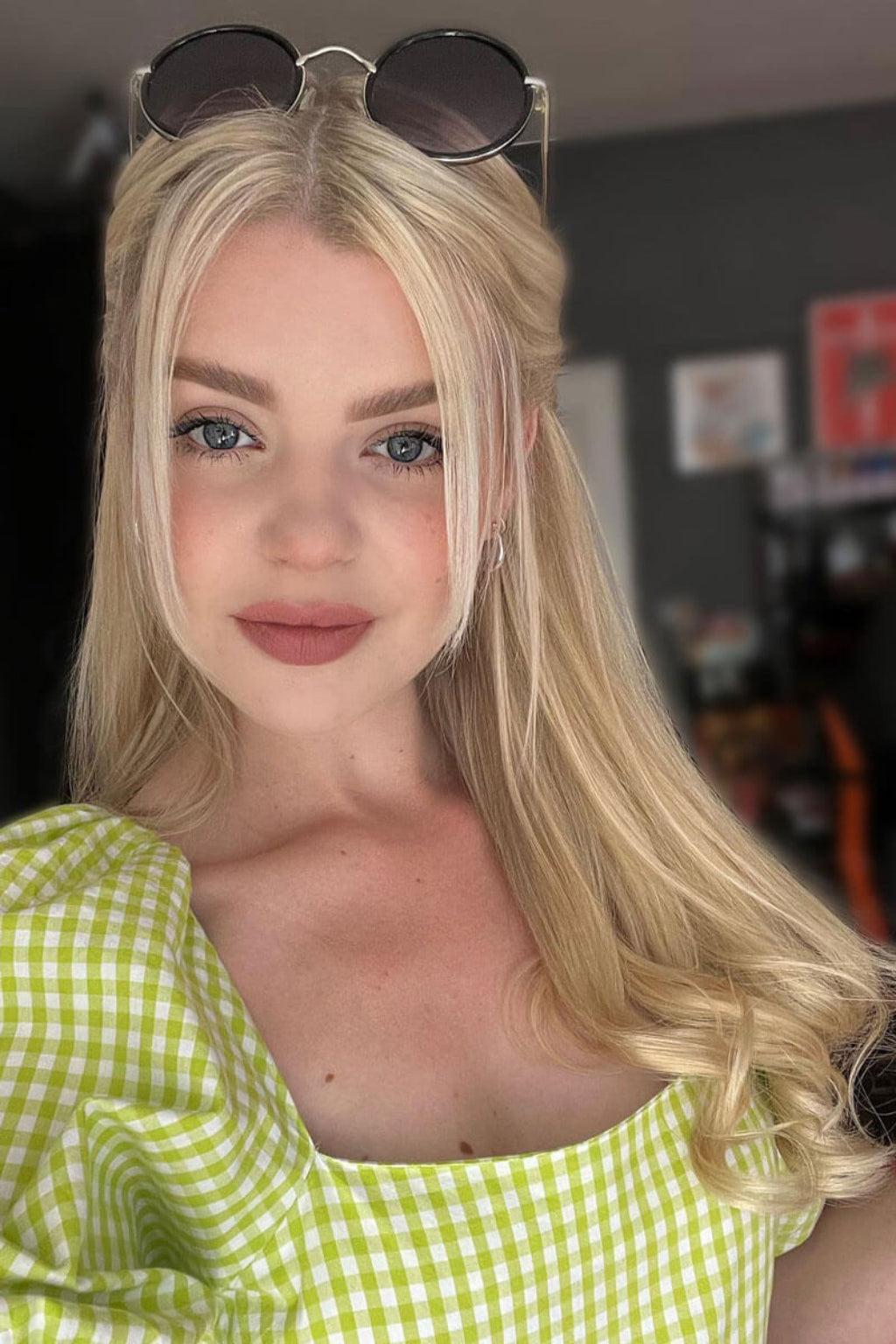 A woman with long blonde hair wearing a green checkered top and sunglasses on her head. Human Hair Extensions, remy hair 613T24