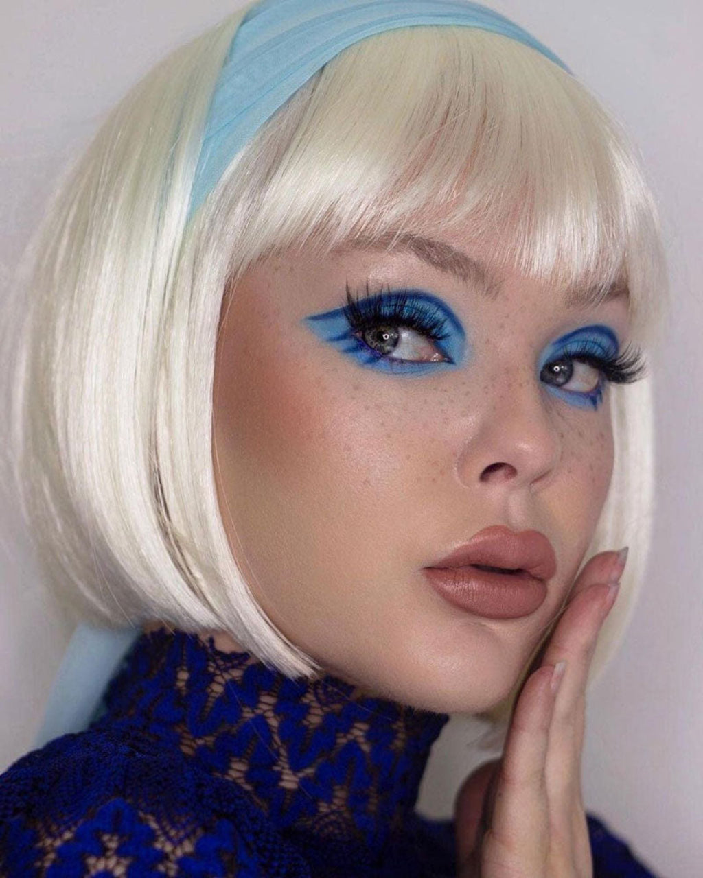 Person with blonde bob haircut and blue headband wearing a blue patterned garment. Platinum blonde bob wig: Carol-Anne